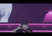a woman singing into a microphone with headphones on her head