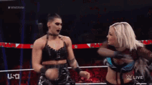 two female wrestlers are standing next to each other in a ring .