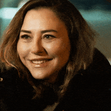 a close up of a woman 's face smiling and wearing a black jacket