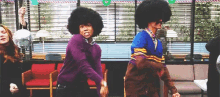 a couple of people with afros are dancing in a room