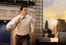 a man in a white shirt and brown pants is running in a city .