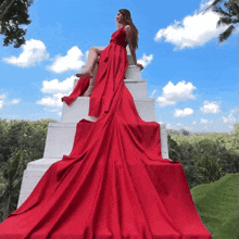 a woman in a red dress sits on a white pyramid