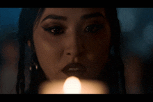 a woman is blowing out a candle with a tear coming out of her eye