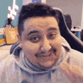 a man with a mustache is sitting in a chair and making a face .