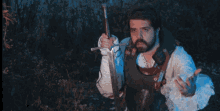 a man with a beard is holding a sword in his right hand