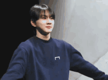 a young man wearing a blue sweatshirt with a white letter l on it