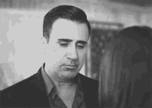 a black and white photo of a man in a suit looking at a woman