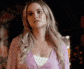 a woman in a purple cardigan is standing in a dark room .