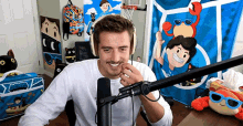 a man wearing headphones is sitting in front of a microphone in a room with a bag that says denis