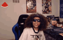 a man wearing sunglasses and headphones is sitting in front of a poster for my hero academia