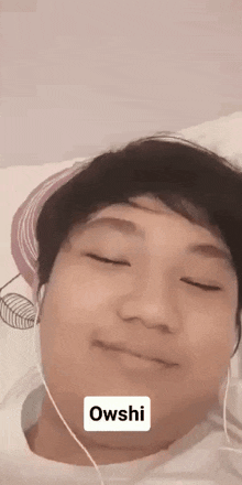 a man wearing headphones is laying on a bed with his eyes closed and a sticker that says owshi