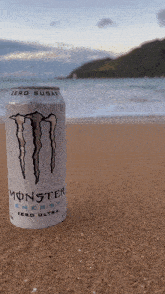 a can of monster energy sits on the beach