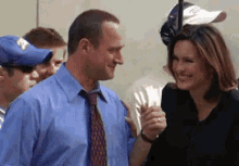 a man in a blue shirt and tie stands next to a woman in a black dress