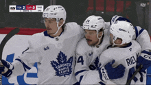a group of toronto maple leafs hockey players are hugging each other