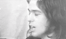 a black and white photo of a man with long hair singing .