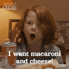 a boy with red hair is sitting at a table with his mouth open and says " i want macaroni and cheese "