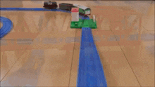 a toy train is going down a wooden track on a wooden floor .