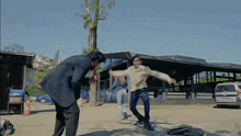 a man in a white shirt is kicking another man in a black suit