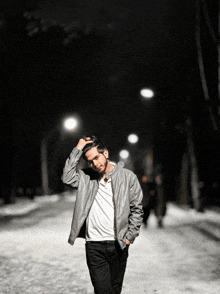 a man in a white shirt and gray jacket stands in a snowy street