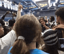 a crowd of people are gathered in a stadium with a sign on the wall that says ' a '