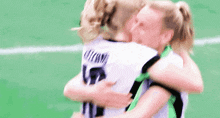 two female soccer players hugging each other on a field .