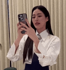 a woman in a white shirt is taking a selfie with her phone