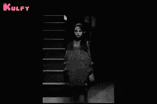 a black and white photo of a girl standing in front of stairs with the words kulfy in pink