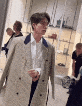 a man in a plaid jacket is standing in front of a mirror in a store