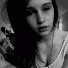 a black and white photo of a woman wearing a white tank top and necklace .