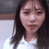 a close up of a woman 's face with a white shirt on looking at the camera .