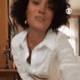 a woman with curly hair is wearing a white shirt and earrings .