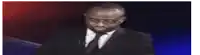 a man in a suit and tie is speaking into a microphone .