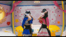 two girls are standing next to each other in a room with a pink wall .