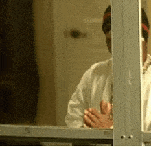 a man in a white shirt looks out of a window