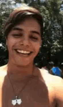 a shirtless young man is smiling and taking a selfie .