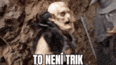 a man in a skeleton mask is standing in front of a rock wall with a sword .