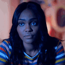 a woman in a striped shirt looks at the camera with a serious look on her face .
