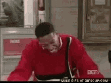 a man in a red sweater is making a funny face in a room .