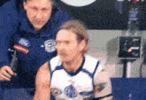 a man wearing a ford jacket stands next to a man wearing a headband
