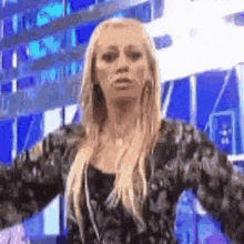 a woman is standing in front of a building with her arms outstretched and making a funny face .