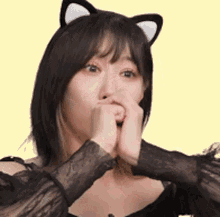 a woman wearing a cat ear headband is covering her mouth with her hands .