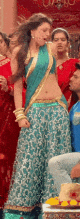 a woman in a blue and gold saree is dancing in a room .