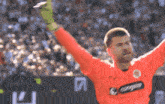 a soccer player wearing an orange jersey with the word compass on the front