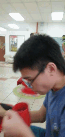 a man in a blue shirt is drinking from a red container