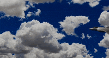 a plane flying through a cloudy blue sky