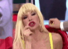 a woman with blonde hair and red lips is wearing a yellow bra and a wig .
