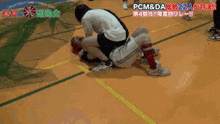 a man is sitting on another man 's shoulders on a basketball court .
