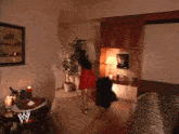 a woman in a red skirt stands in a living room with a w logo on the table