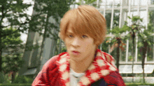 a blurry picture of a young man with blonde hair wearing a red and white jacket