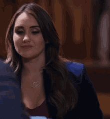 a woman wearing a blue jacket and a necklace with two rings